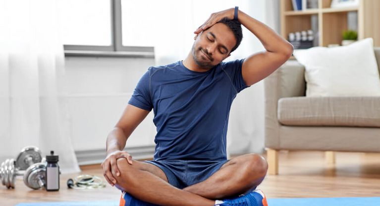 Junger athletischer Mann macht Dehnungsübungen zu Hause