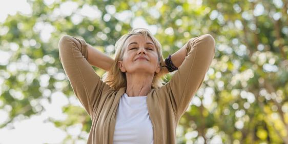 Eine blonde Frau entspannt bei einem Spaziergang unter Bäumen